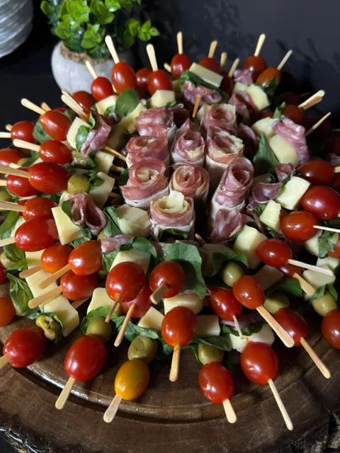 Espetinhos de tomate, queijo e frios em tábua redonda