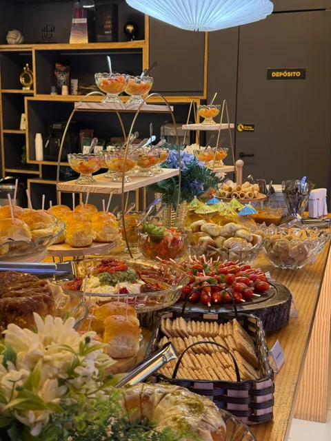 Buffet de coffee break com frutas em taças, salgados e sanduíches